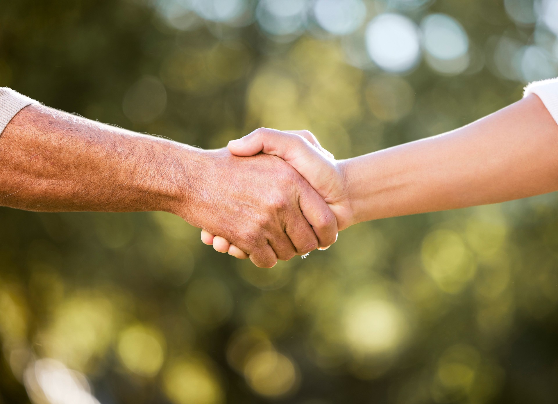 Tiro de dois homens irreconhecíveis apertando as mãos ao ar livre